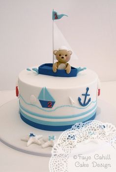 a white and blue cake with a teddy bear on top