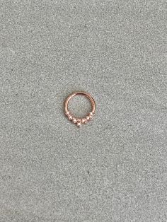 a small rose gold ring sitting on top of a gray surface with tiny pink stones