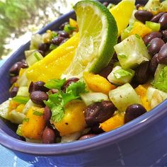 a blue bowl filled with black beans, avocado and lemon wedged salad