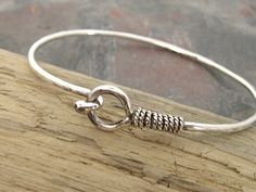 This simple bracelet is a great bangle to wear alone or it can be a perfect layering piece. It's forged from sturdy 12 gauge wire and is work hardened to keep its shape. Small hook fits easily into the keyhole closure and will stay securely on your wrist. Oxidized sterling twist wire is wrapped around the top shaft to add detail. Polished to a high shine and made to order. Allow 10 business days for fabrication. XSmall - fits 5-5.5 inch wrist Small - fits 5.5-6 inch wrist Medium - fits 6-6.5 inc Sterling Silver Bangle With Lobster Clasp, Simple Adjustable Bracelet Bangle, Simple Adjustable Bangle Bracelet, Everyday Sterling Silver Bangle, Twisted Wire, Simple Bracelets, Artisan Jewelry, Handmade Silver, Bangle Bracelets