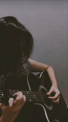 a person playing an acoustic guitar in front of a wall