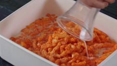 a person pouring something into a white container filled with cereals and other food items