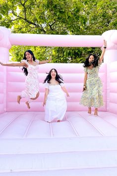 three women jumping in an inflatable pool