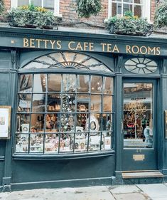 a store front with lots of windows and plants on the top floor, along with signs that read betty's cafe tea rooms