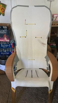 a chair made out of cardboard sitting on top of carpeted floor next to a book shelf