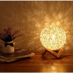 a light that is sitting on top of a table next to some books and a vase