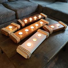 candles are arranged in the shape of boats on a table next to couches and pillows