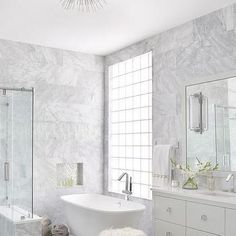 a white bathroom with marble walls and floors