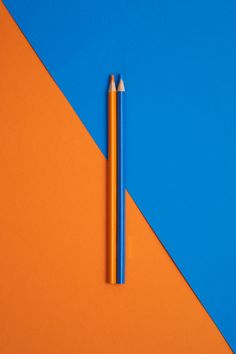 two pencils on an orange and blue background