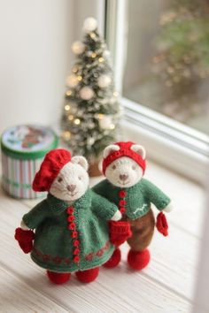 two teddy bears are dressed in green and red outfits next to a small christmas tree