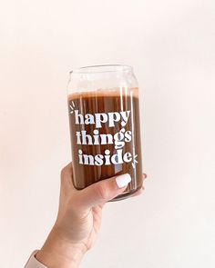 a person holding up a glass that says happy things inside it with the words inside