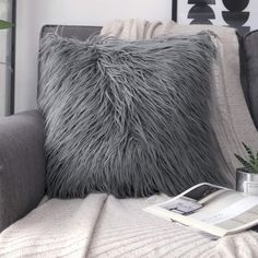 a gray couch with a book on it and a plant in the corner next to it