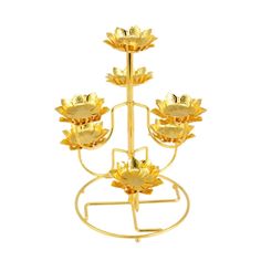 three tiered gold plated metal candle holder with flowers on each side and four candles in the middle