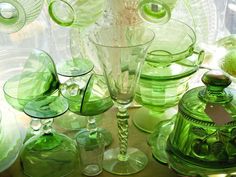 many green glass dishes and vases on a table