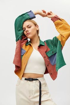 a woman is posing with her hands on her head and wearing a colorful jacket over her shoulders