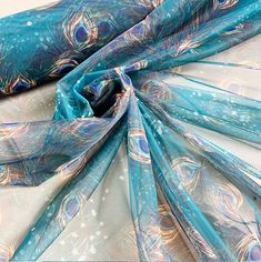 an image of a blue and white scarf with feathers on the bottom, as if it were made out of silk