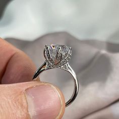 a close up of a person holding a ring with a diamond in it's center