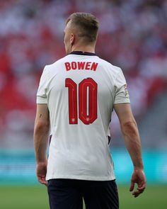 a soccer player is standing on the field with his back to the camera and looking down