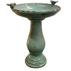 an old green birdbath with two birds perched on it's top and bottom