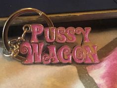 a keychain with the word pussyy bacon on it sitting on a table