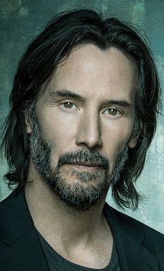 a man with long hair and beard wearing a black shirt is looking at the camera