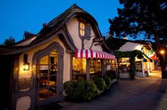 the outside of a small building with awnings and lights on it at night