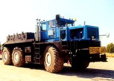 a large blue truck parked on top of a dirt field