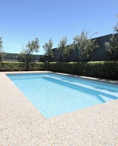 an empty swimming pool surrounded by hedges and trees