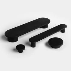 three black knobs and two round knobs on a white surface