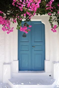 a blue door with pink flowers growing over it's sides and below the doors