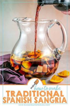 a pitcher filled with liquid sitting on top of a table next to sliced oranges