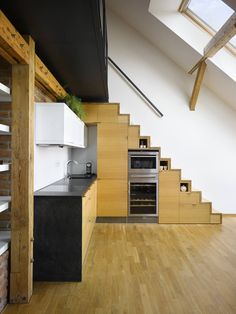 an open kitchen with stairs leading up to the upper floor and above it is a stainless steel oven