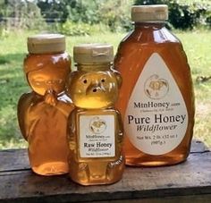 three bottles of honey sitting on top of a wooden table