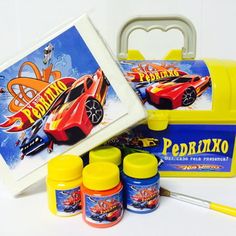 a yellow lunch box with some paint and markers in it, next to two small tins