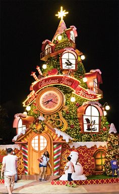 people are standing in front of a christmas tree with lights and decorations on the top