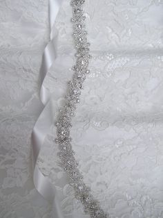 "Sparkling silver bridal sash adorned with rhinestones. Securely fastened onto a quality double faced satin ribbon which ties into a bow and drapes down the back of your wedding dress. Perfect finishing touch for your wedding attire! Please make your choice of rhinestone trim length, ribbon colour, no ribbon or hook and eye closure from the drop down menus. Contact me if you have a custom length requirement. Ribbon options to purchase: You may purchase just the rhinestone trim ( no ribbon ) The Elegant Silver Bedazzled Sash, Elegant Bedazzled Silver Sash, Elegant Silver Bedazzled Sashes, Elegant Bedazzled Silver Sashes, Silver Bedazzled Bridal Belt For Wedding, Bedazzled White Bridal Belt For Wedding, Fitted Silver Bridal Belt For Bride, Silver Fitted Bridal Belt, White Crystal Wedding Sash