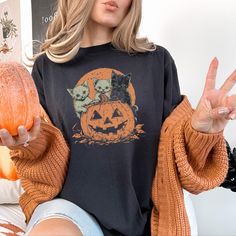 Cat-o-Ween T-Shirt  Get ready for a spook-tacular Halloween with our adorable "Cat-o-Ween" graphic tee, featuring vintage-style kittens peeking out of a Jack-O-Lantern. Design Details: 🎃🐈 *  Unique, distressed vintage-style design *  Kittens inside a Halloween Jack-O-Lantern *  Perfect blend of spooky and cute Available Color: 🌈 *  Black Quality Features:  *  Printed on Comfort Colors 1717 series garment-dyed t-shirt *  100% US cotton, ethically grown and harvested *  Soft-washed, garment-dye Spooky Cats, Halloween T Shirts, Color Charts, Dyed Fabric, Cat Tshirt, Jack O Lantern, Dye T Shirt, Tshirt Colors, Vintage Stil