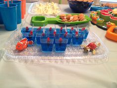 there are many plastic cups and trays with food on the table in front of them