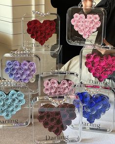 four clear acrylic boxes with roses in the shape of hearts