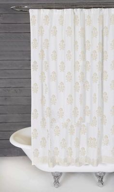 a white shower curtain hanging on the side of a bath tub