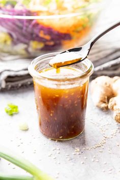 a spoon full of sauce sitting on top of a table next to garlic and ginger