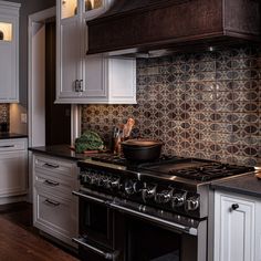 a stove top oven sitting inside of a kitchen next to white cabinets and counter tops