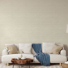 a living room with a white couch and coffee table in front of a beige wall