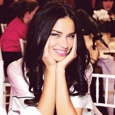 a woman sitting at a table with her hands on her face and smiling for the camera