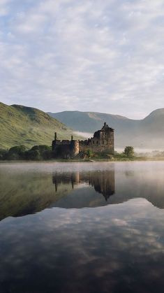 a castle sitting on top of a lake surrounded by mountains