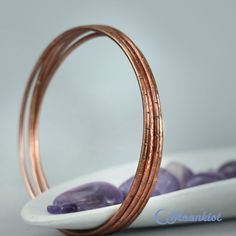 "This set of 4 handmade copper bangle bracelets absolutely sing while you are wearing them! Made from 12 gauge copper wire that has been soldered, then textured, they are light and comfortable, and can be custom made to order in whatever size you would prefer. They can also be sealed, to help keep the copper from reacting with your skin and to help keep the copper bright and shiny, or antiqued to give the copper a darker finish. Just let me know your preference on checkout. Bangle Sizes: (Rememb Gold Electroformed Bracelets For Gift, Copper Bangle Gift, Handmade Copper Bangle, Rose Gold Copper Bangle As Gift, Bohemian Rose Gold Bangle For Gift, Rose Gold Bohemian Bangle As Gift, Bohemian Rose Gold Bangle Gift, Copper Bangles, Handmade Bangle Bracelets