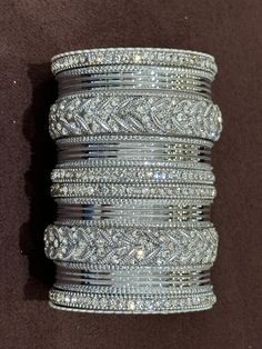 NAZRANAA JEWELS OFFERS A GREAT RANGE OF INDIAN JEWELRY FOR TODAY'S WOMAN WITH THE LATEST DESIGNS. THE BRAND IS COMMITTED TO PROVIDING ITS CUSTOMERS WITH THE HIGHEST QUALITY OF GOODS AND NEWEST DESIGNS. IT IS SUITED FOR A WOMAN WHO IS LOOKING TO STAY DATED WITH THE LATEST TRENDS. RADIANT SILVER BANGLES IS A PERFECT ACCESSORY FOR ANY NIGHT EVENT. IT IS SURE TO MAKE YOU STAND OUT IN A CROWDED ROOM.  Traditional Indian Jewelry: Slight Color variations possible due to difference in screen and photograph.If you are interested in purchasing this item and have any questions about this item, please feel free to send us a message. Care instructions Keep Jewelry away from direct heat, water, perfumes, deodorants and other strong chemicals as they may react with the metal or plating.  Perspiration (sw Wedding Bangles Indian, Crowded Room, Wedding Bangles, Traditional Indian Jewellery, Bangles Indian, Stone Bangle, Bridal Stores, Clear Stone, Stone Work