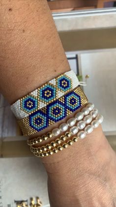 a woman's arm with three bracelets on top of it and pearls around the wrist