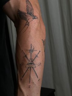 a man's arm with tattoos on it and a bird flying over the compass