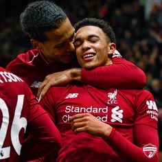 two liverpool players hugging each other in front of an audience